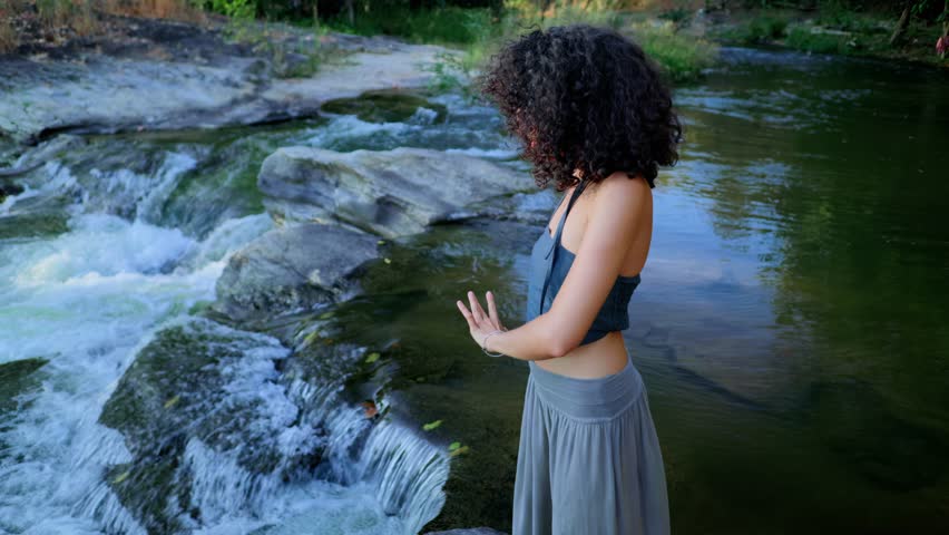 A Serene Reflection: A Young Woman Embracing Nature's Beauty Beside a Flowing Stream, Capturing Moments of Tranquility and Connection with the Environment
