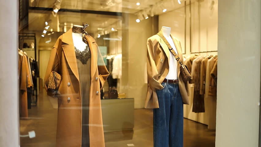 Showcase of a fashionable clothing store in Rome, Italy with mannequins dressed in elegant coats and accessories. Perfect editorial footage illustrating urban fashion, European lifestyle, and shopping