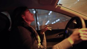 Latina woman driving car at night through city tunnel, one hand on steering wheel, serious expression, light reflections on windshield, motion and urban commute - Powered by Shutterstock - Get 15% off with code: PIKWIZARD15