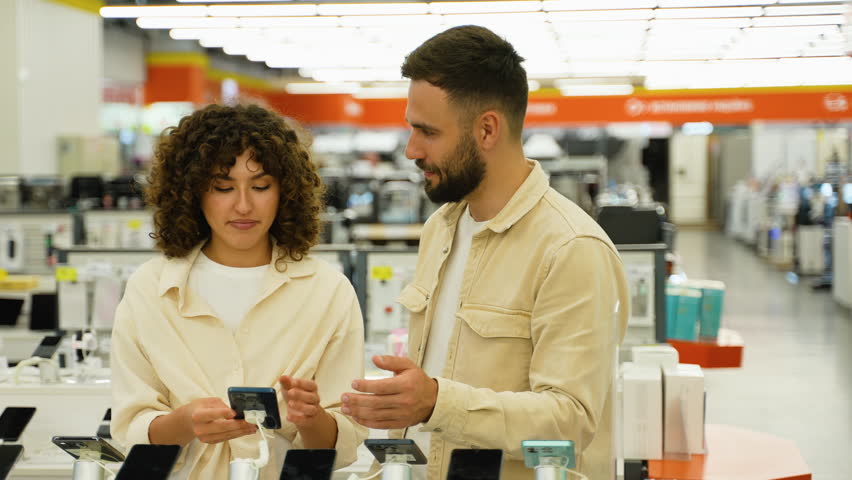 Couple choosing smartphone in electronics store on Black Friday