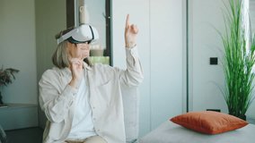 Senior woman engages with virtual reality technology in a modern living room, experiencing new adventures and activities at home - Powered by Shutterstock - Get 15% off with code: PIKWIZARD15