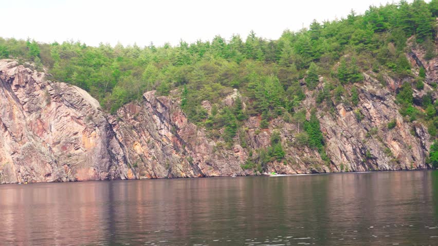 A grandparent takes their grandson kayaking on a large Canadian lake.