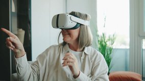 Senior woman exploring virtual reality inside her modern home while using VR headset during a sunny afternoon - Powered by Shutterstock - Get 15% off with code: PIKWIZARD15