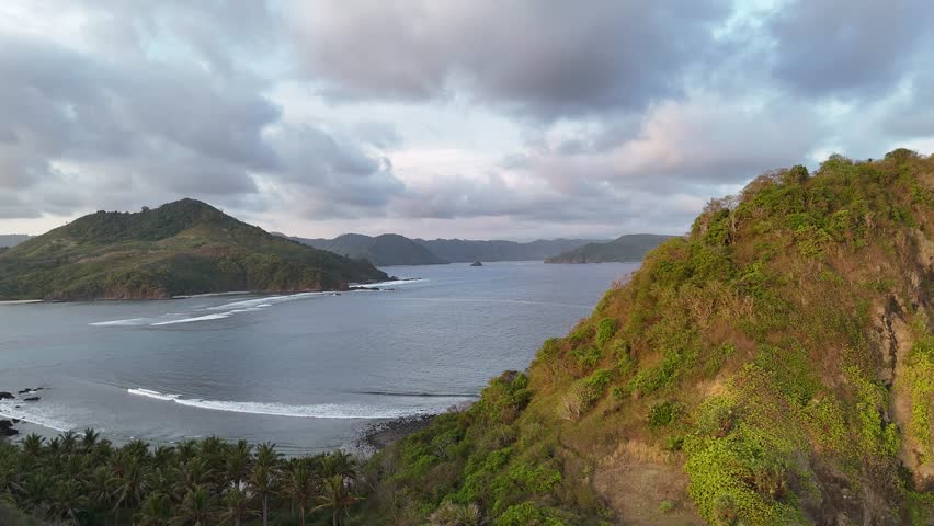 Tropical Island Coastline Aerial View with Green Hills and Cloudy Sky