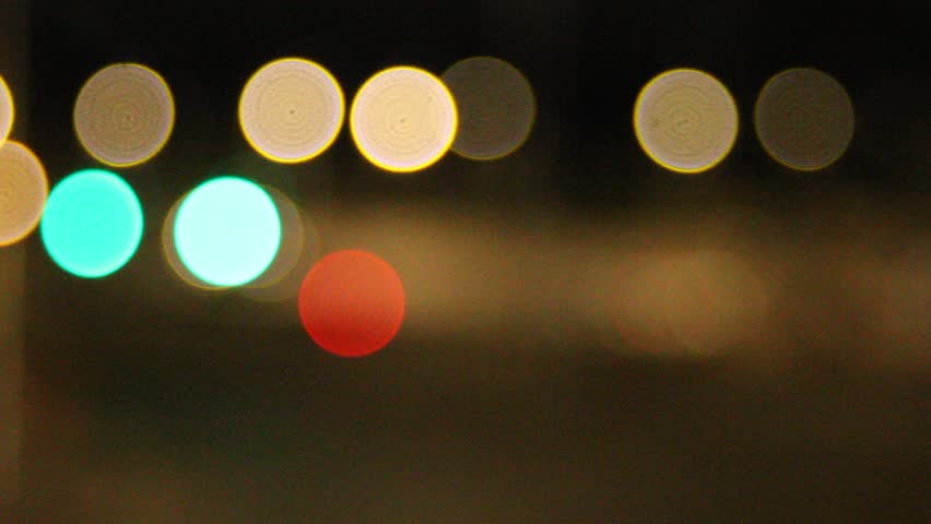 Stylized lens-orbed video of traffic passing on a busy road. Blurred lights create dynamic bokeh effects, capturing movement, speed, and urban nightlife in an artistic, cinematic style.