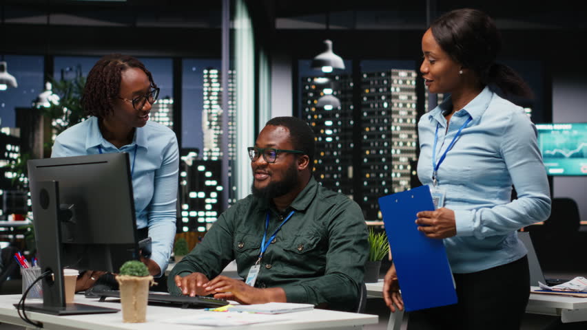 Team of black office employees works with data insights and performance metrics, aligning vision and objectives to drive success within a multinational company environment at night. Camera B.