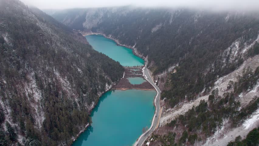 Drone view of Jiuzhaigou National Park in spring in Sichuan Province China. It features cascading waterfalls, turquoise blue lakes, and stunning mountain valleys. 4K real time footage travel concept.