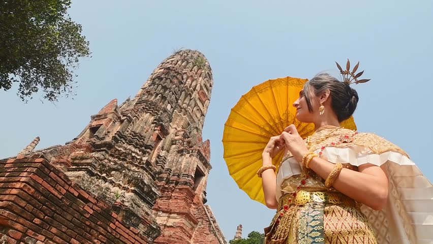 Thailand, Ayutthaya - march 15th, 2023: Woman in traditional Thai dress pose sightseeing visit ancient Buddha statue.Ayutthaya historical park. UNESCO World Heritage Site