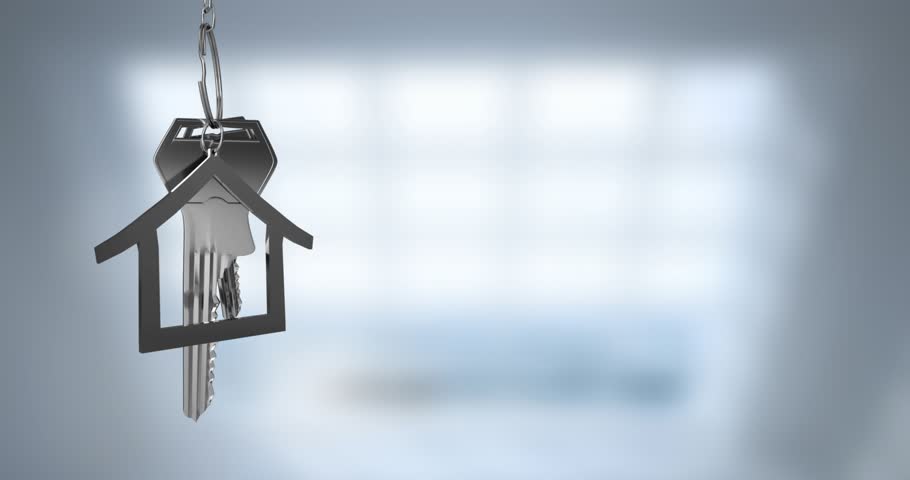 Animation of silver key with house key fob and copy space over out of focus interiors. Home ownership and property concept digitally generated image.