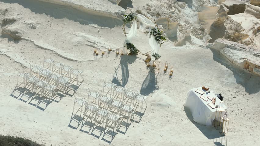 An enchanting wedding ceremony setup features white chairs, floral decorations, and a lovely arch in a unique outdoor location. This picturesque scene invites guests to celebrate love.