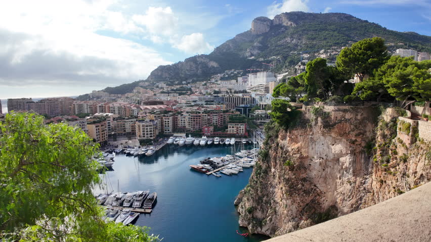 High-angle view of Port de Fontvieille in Monaco, showcasing colorful buildings, luxury yachts, and the surrounding mountainous landscape