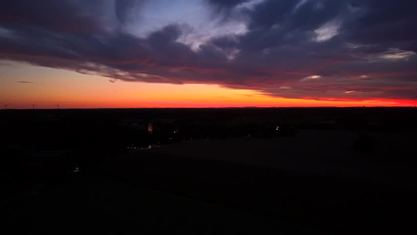 Headlights of cars on early morning with spectacular colored sky at sunrise. Drone wide shot. Peaceful scene in American suburbia. Orange sky with dramatic cloudscape.
