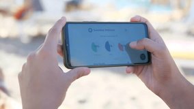 A man's hands on a beach use a health application to access detailed sleep metrics and statistics, reading the comprehensive data analysis. This scene is perfect for content about wellness tracking - Powered by Shutterstock - Get 15% off with code: PIKWIZARD15