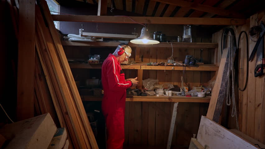 A technician in work clothes checks a part under the light of an incandescent lamp.