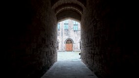 A dark passage leads to a sunlit castle courtyard, framed by archways and stone walls. - Powered by Shutterstock - Get 15% off with code: PIKWIZARD15