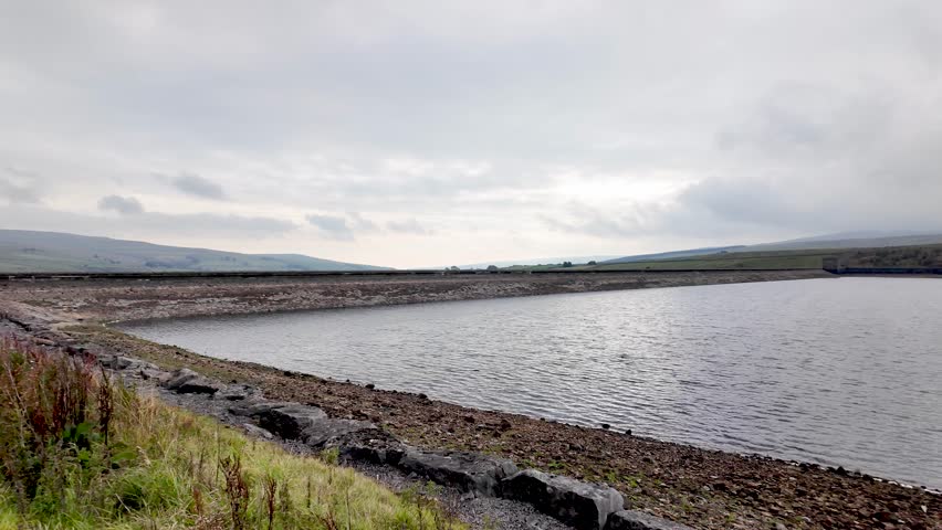 Burnhope Reservoir showcasing its retaining dam under an overcast sky in rural England