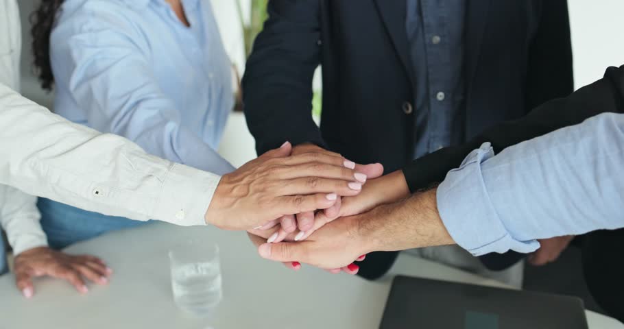 Multi generational people working inside business office - Colleagues stacking hands - Teamwork and job meeting concept