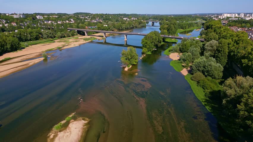 Pont Mirabeau bridge crossing wide Loire river with sandbanks, City of Tours in background. France. Aerial drone forward view