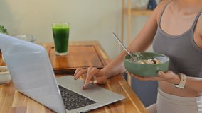 Healthy lifestyle concept with woman eating yogurt while working online in a bright kitchen. - Powered by Shutterstock - Get 15% off with code: PIKWIZARD15