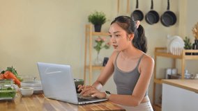 Morning wellness routine showing woman in sportswear eating yogurt bowl beside a laptop and fresh ingredients. - Powered by Shutterstock - Get 15% off with code: PIKWIZARD15
