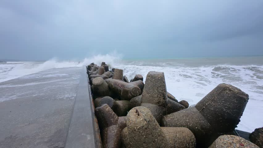 Powerful storm waves crashing against a pier, first-person view of dramatic ocean spray and rough sea