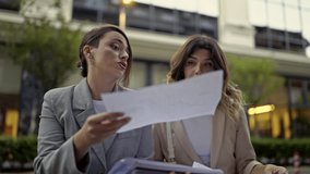 Professional business women engage in an important meeting, discussing reports while working together in an outdoor urban environment. They analyze financial data and strategic for their project. - Powered by Shutterstock - Get 15% off with code: PIKWIZARD15