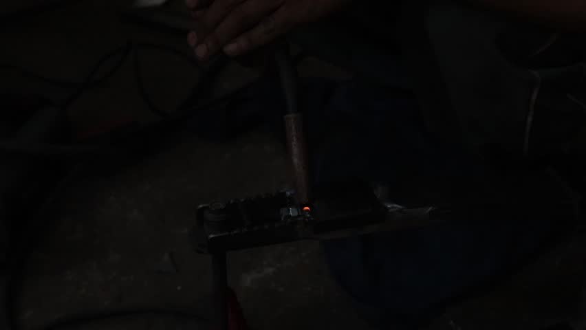 Skilled worker performs intense welding, creating bright blue spark and vibrant light. Metal joining powers manufacturing and construction industry, illuminating dark workspace with precision