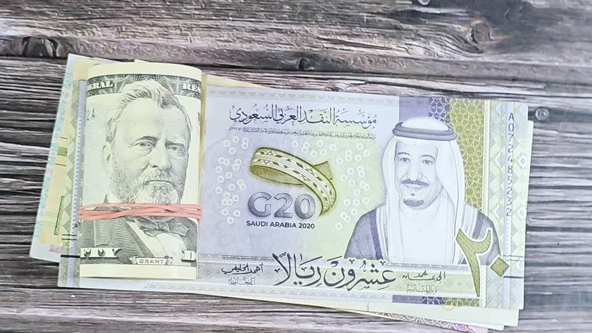 Saudi Arabian money SAR riyals bills and 50 USD fifty American dollars banknotes cash money rolled up with a rubber band, features Ulysses S. Grant, American and Saudi money, money exchange rate