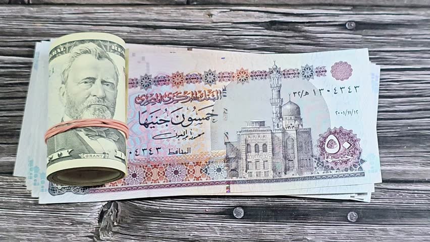 Egyptian money 50 EGP LE pounds bills and 50 USD fifty American dollars banknotes cash money rolled up with a rubber band, features Ulysses S. Grant, American and Egyptian money, money exchange rate