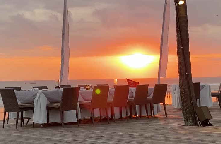 Scene of elegant seaside dining in Seminyak with sunset glow over the ocean horizon