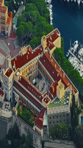  Aerial view of the city center of Monaco. Establishing shot showcases luxury yachts moored in Monaco Bay, the Palais Princier de Monaco, and luxury apartment buildings of Monte Carlo