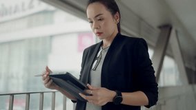 Serious Asian businesswoman using tablet in modern city walkway. Concept of remote work, digital transformation, analysis, and technology-driven career. - Powered by Shutterstock - Get 15% off with code: PIKWIZARD15