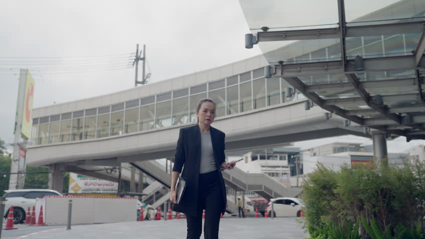Busy Asian businesswoman looking at smartwatch while holding tablet and smartphone. Concept of multitasking, time management, and modern professional life. - Powered by Shutterstock - Get 15% off with code: PIKWIZARD15