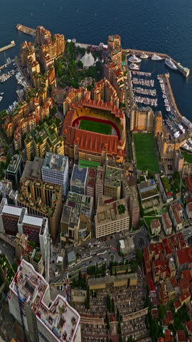  Aerial view of the city center of Monaco. Establishing shot showcases luxury yachts moored in Monaco Bay, the Palais Princier de Monaco, and luxury apartment buildings of Monte Carlo