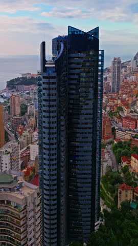  Aerial view of the city center of Monaco. Establishing shot showcases luxury yachts moored in Monaco Bay, the Palais Princier de Monaco, and luxury apartment buildings of Monte Carlo