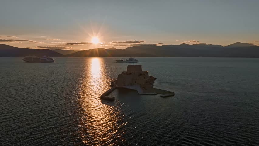 Aerial view of the Bourtzi castle surrounded by the sea, with the sun reflecting on the water, creating a stunning scene, Nafplion, Argolis, Greece.