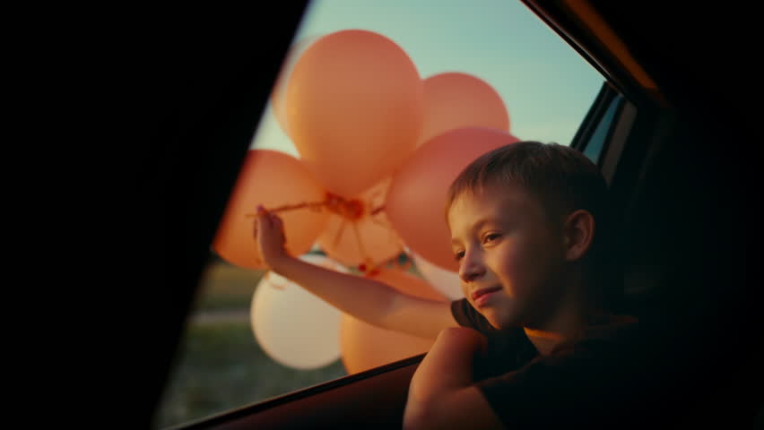 Little child dreaming of future, sitting inside car moving in nature, portrait. Happy childhood moments, having fun and joy, beautiful sunset or sunrise shine on cute face of carefree preschool boy