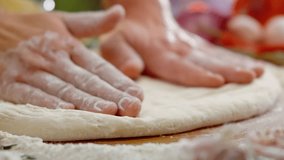 Skillful chef's hands kneading and flattening fresh pizza dough on a floured wooden surface, preparing the base for an authentic italian meal in a restaurant kitchen with fresh ingredients - Powered by Shutterstock - Get 15% off with code: PIKWIZARD15