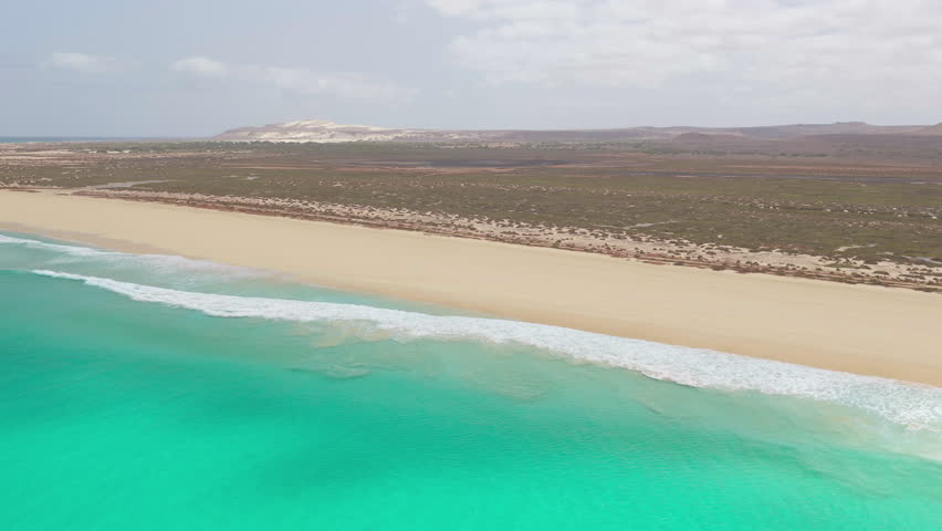 Drone footage of Santa Monica Beach,showcasing endless white sand, turquoise waves, and a pristine,summer concept,Boa Vista, Cape Verde.