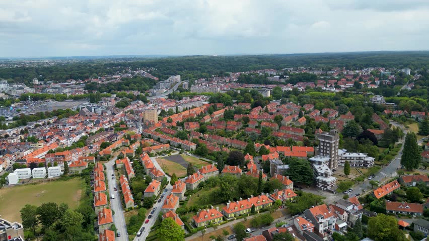 Aerial view of residential buildings with orange rooftops and lush green trees contrasting against the sky, Watermael-Boitsfort, Bruxelles, Belgium.