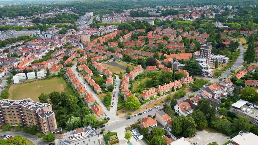 Aerial view of rows of houses with red roofs contrasting with the lush green trees along 1 Avenue des Nymphes, Watermael-Boitsfort, Bruxelles, Belgium.