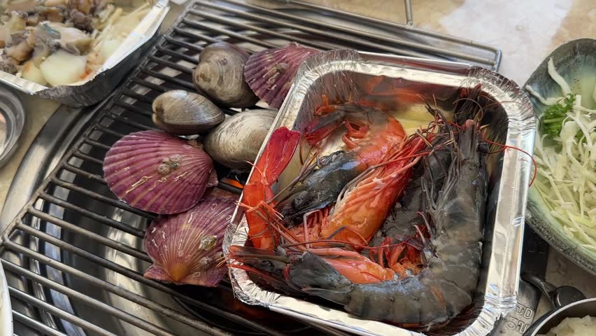 Famous seafood restaurant in Haeundae Beach, Busan, South Korea. Fresh assorted shellfish cooking over a traditional charcoal bbq grill.