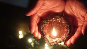 Indian woman celebrating Diwali, holding a glowing diya in both hands with festive lights in the background.
 - Powered by Shutterstock - Get 15% off with code: PIKWIZARD15