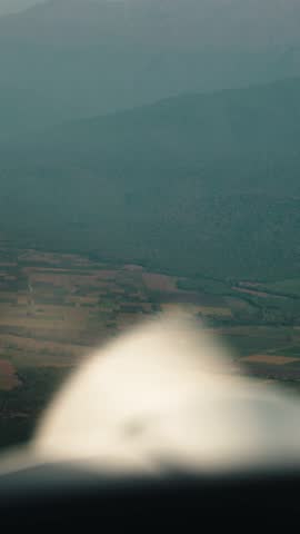 A small plane flying over colorful autumn landscapes at sunset