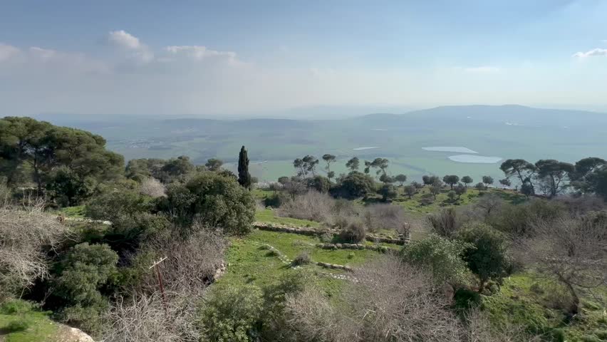 View from Mount Tabor in Israel of the valley below, mountains, and cypress trees on a clear bright day.