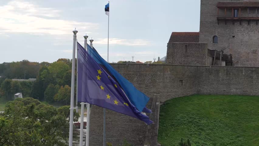 European Union Flag with NATO Logo Flying over Historic Hermann Castle in Narva, Symbolizing Estonian Security and Western Alliance
