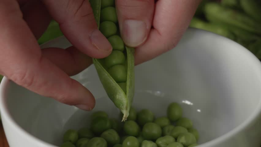 Slow Motion Shelling of Fresh Green Peas Falling into Bowl