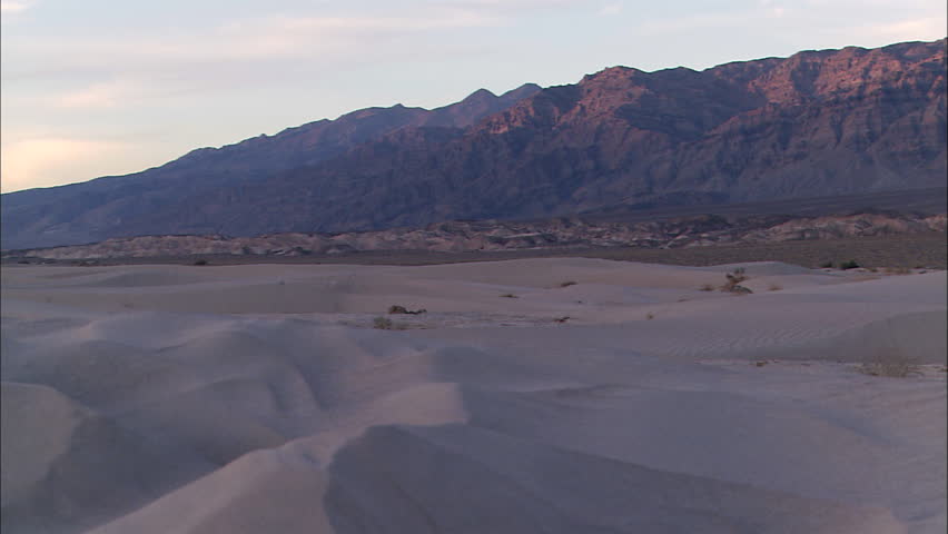 Pan across desert of Death Valley to mountains at sunset