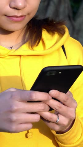 Close up of asian hands woman using a smartphone in beutiful park with trees background at Taipei. Girl tourist travel and used phone device and write text in Taiwan. Person holding a mobile