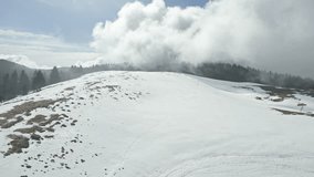 Drone shot of a gentle snowy ridge with fence posts as clouds drift above the Cansiglio plateau in Italy; forested hills frame the horizon. - Powered by Shutterstock - Get 15% off with code: PIKWIZARD15